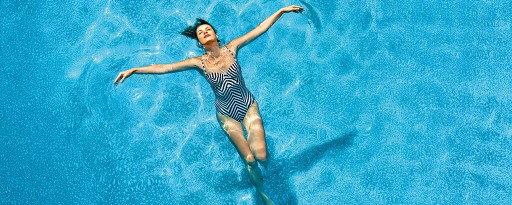 Eine Frau in einem Badeanzug schwimmt mit geschlossenen Augen in einem Pool