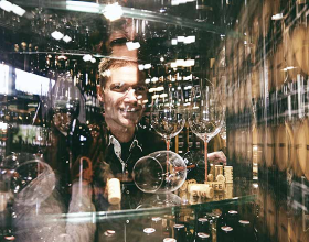 Verschiedene Weine in einer Glasvitrine in die eine Person hineinschaut