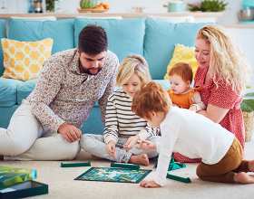Eine Familie beim Spielen eines Brettspiels auf dem Boden