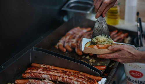 Ein Koch garniert einen Hotdog mit frischem Sauerkraut
