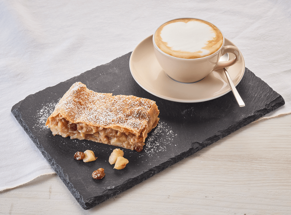Ein Stück Apfelstrudel und eine Tasse Cappuccino auf einem Tisch