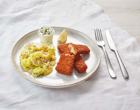 Backfisch mit Kartoffelsalat, Remoulade und Zitronen auf einem Teller