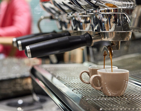 Frischer Kaffee rinnt aus einer Kaffemaschine in zwei Espressotassen