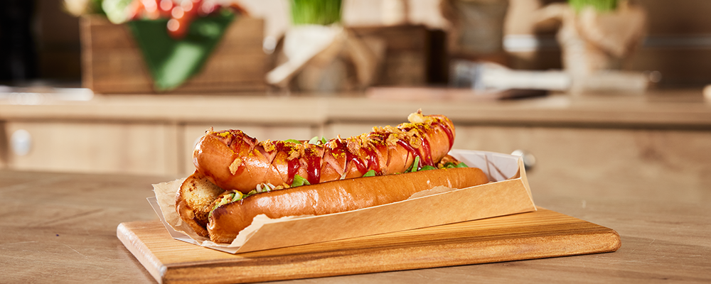 Ein Curry-Hotdog mit einer Currywurst und Currysauce in einem Brot