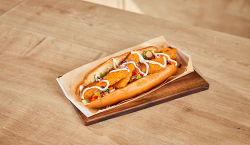 Ein Fish-Dog mit Backfisch, Burkenrelish, Mayonnaise und Jungzwiebeln