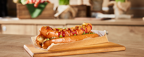 Ein Curry-Hotdog mit einer Currywurst und Currysauce in einem Brot