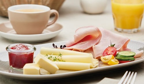 Käse, Schinken, Gurke, Tomaten, Butter und Marmelade auf einem Teller