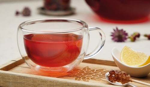 Roter Tee in einer durchsichtigen Tasse mit einer Scheibe Zitrone