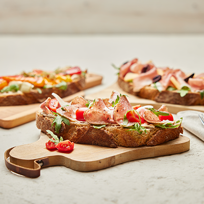 Drei einzelne Brote belegt mit Salami, Prosciutto, Tomaten und mehr