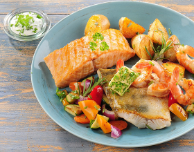 Ein Teller mit zwei gebratenen Stücken Lachs und Ofengemüse