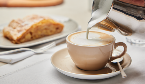 Eine Tasse Cappuccino und ein Stück Apfelstrudel auf einem Teller