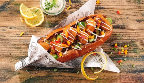 Hotdog mit weißer Sauce, Paprika, Gurke und mehr