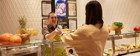 Eine Freu bekommt ein Gericht im INTERSPAR-Restaurant überreicht