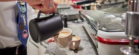 Ein Mann schenkt Kaffee in eine Tasse