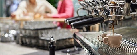 Frischer Kaffee läuft aus einer Kaffeemaschine in zwei Espressotassen