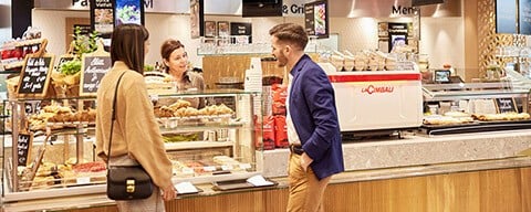 Ein Mann und eine Frau bekommen Kaffee an einer INTERSPAR Kaffeebar