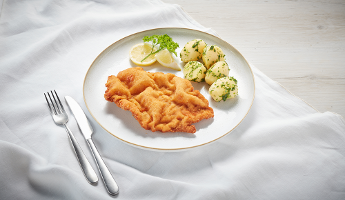 Ein Wiener Schnitzel mit Petersilienkartoffeln und Zitronenscheiben