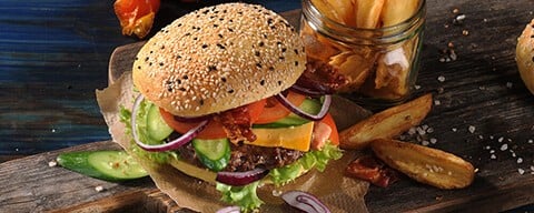 Ein Burger mit einem Sesam-Brot und Kartoffelwedges