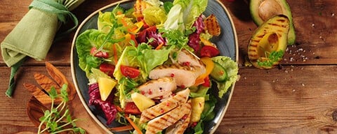 Ein frischer Salat mit Putenstreifen, Gurken und mehr in einem Teller