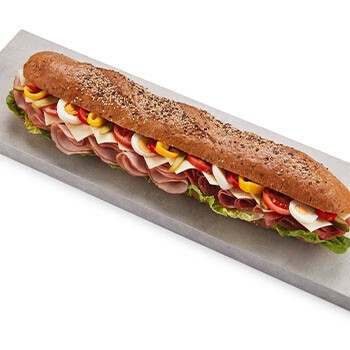 Ein Riesenkornspitz belegt mit Schinken, Paprika, Salami, Salat und mehr