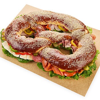 Eine Partybreze mit Sesamkörnern, Käse, Salami, Tomate und mehr
