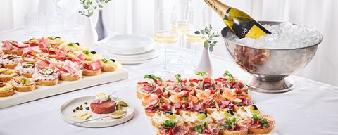 Eine gedeckter Tisch mit Brötchen-Platten und Getränken