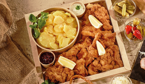 Eine Backhendlbox mit Kartoffelsalat, Preiselbeeren und Sauce Tartare