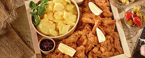 Eine Backhendlbox mit Kartoffelsalat, Preiselbeeren und Sauce Tartare