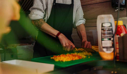 Ein Mann in einem Foodtruck wendet Hotdogs auf einem Grill