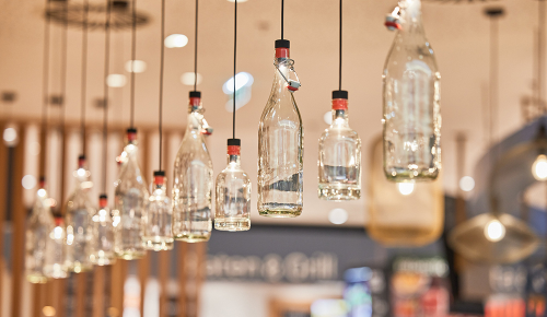 Mehrere leere Glasflaschen hängen mit einer Schnur von der Decke