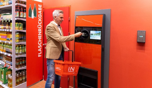 Ein Mann beim Zurückgeben von Pfandflaschen an einem Automaten