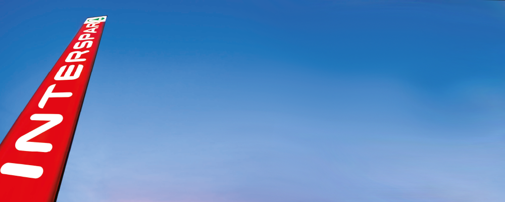 Ein INTERSPAR Pylon ragt in einen blauen Himmel