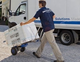 Ein Mann beim Transport eines Großgerätes mit einem Rollwagen