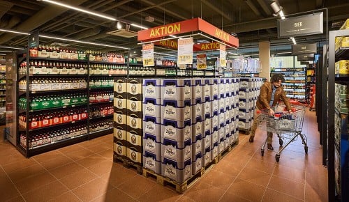 Zwei Personen mit einem Einkaufswagen beim Einkaufen in einer Getränkeabteilung