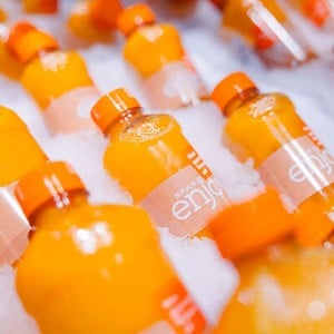 Mehrere SPAR Enjoy Orangensaftflaschen in einer Eiskiste