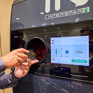 Eine Person legt eine Flasche in einen Flaschenautomaten