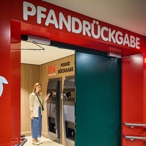 Eine Frau bei der Rückgabe einer Pfandflasche an einem Flaschenautomaten