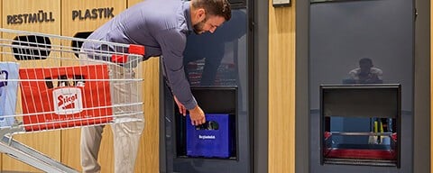 Ein Mann bei der Rückgabe eines Getränkekastens an einem Automaten
