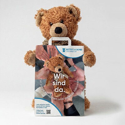 Ein kleiner Teddybär mit einer Papiertragetasche