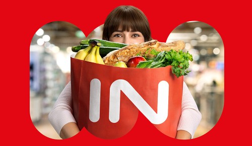Eine junge Frau mit einem INTERSPAR-Papiersackerl voller Produkte in den Armen