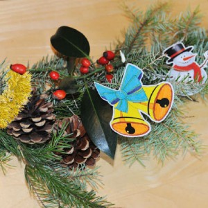 Adventgirlande mit Tannenzapfen, Hagebutten, sowie einem Schneemann und Glocken aus Papier