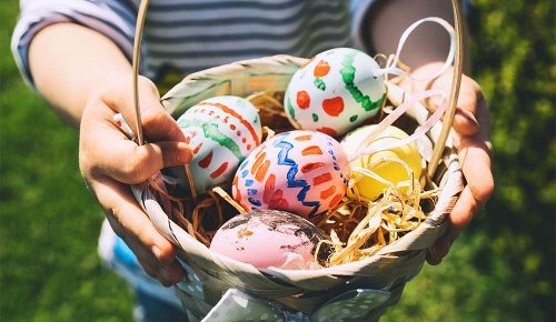 Ein Kind hält ein Nest voller Ostereier in den Händen