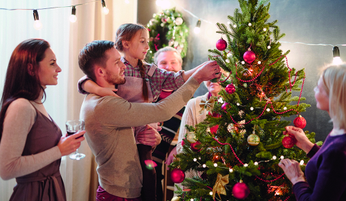 Zwei Erwachsene und ein Kind beim Anschauen eines Christbaumes