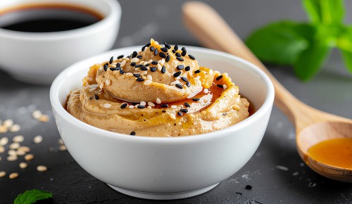Ein weißes Schälchen gefüllt mit einer beigen Paste bestehend aus Miso, Sesam und Reisessig