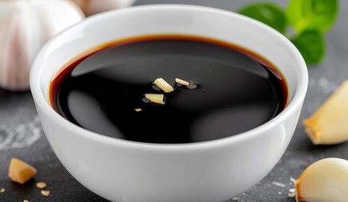 Ein weißes Schälchen gefüllt mit einer glänzenden Sauce bestehend aus Sojasauce, Honig, Ingwer und Knoblauch