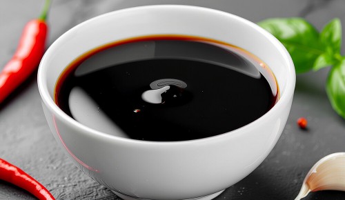 Ein weißes Schälchen gefüllt mit einer glänzenden Sauce bestehend aus Sojasauce, Reisessig, Ingwer und Knoblauch