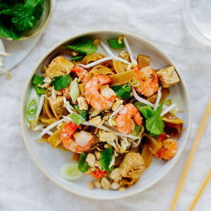 SPAR Mahlzeit Pad Thai auf einem hellen Teller mit Stäbchen und einen Glas Wasser