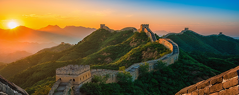 Die Chinesische Mauer schlängelt sich im Sonnenuntergang durch die bergige Landschaft