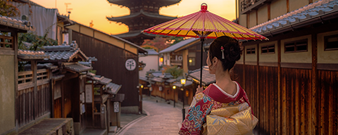 Eine Frau in einem japanischen Kimono spaziert über eine alte japanische Straße mit einer Pagode im Hintergrund