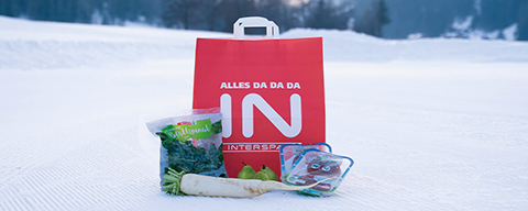 Eine INTERSPAR-Einkaufstasche mit verschiedenen Lebensmitteln im Schnee